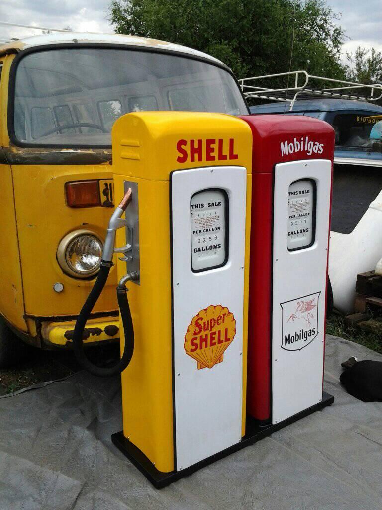 Retro-inspired petrol pump display pieces beside a vintage vehicle